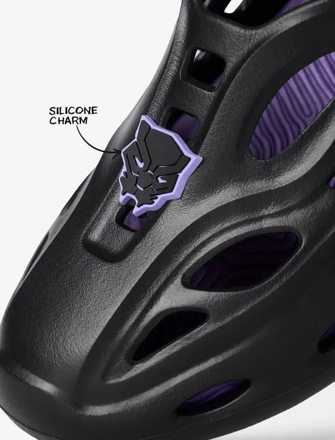 Black sandal with purple accents and a silicone charm on a white background
