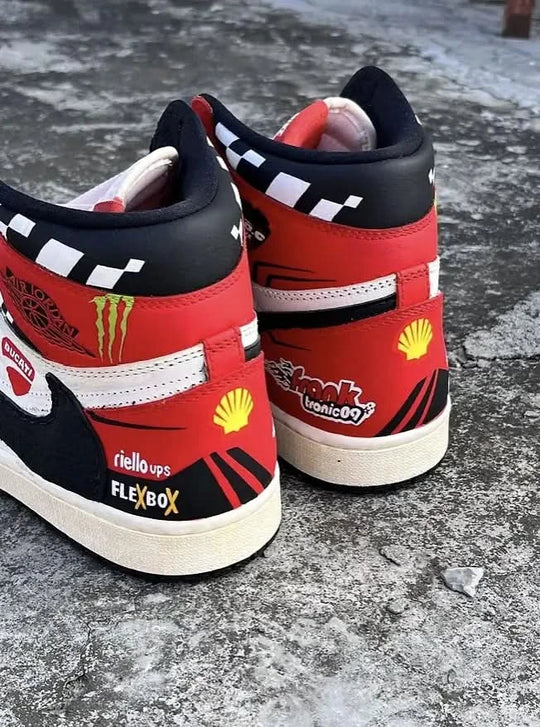 Red high-top sneakers with various logos on a concrete surface